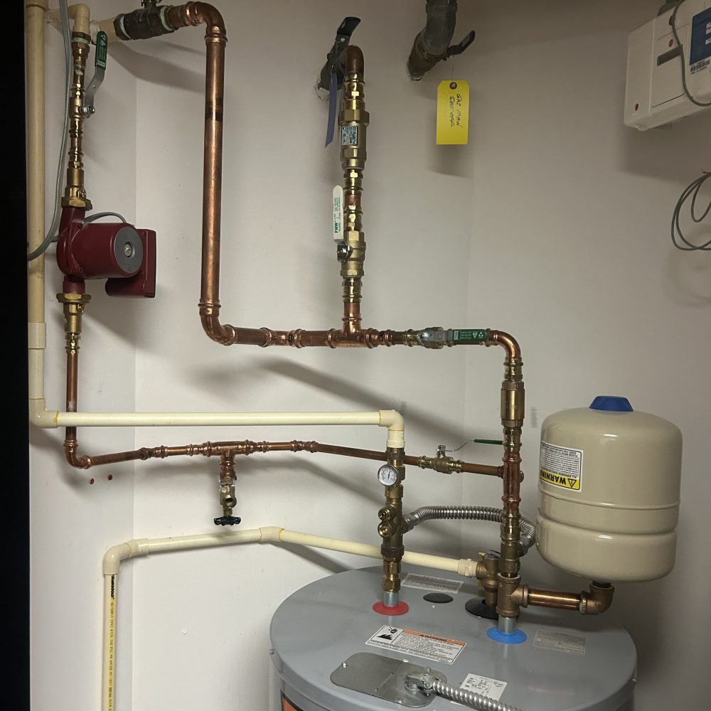 Residential copper plumbing pipes and water supply connections in a utility area.
