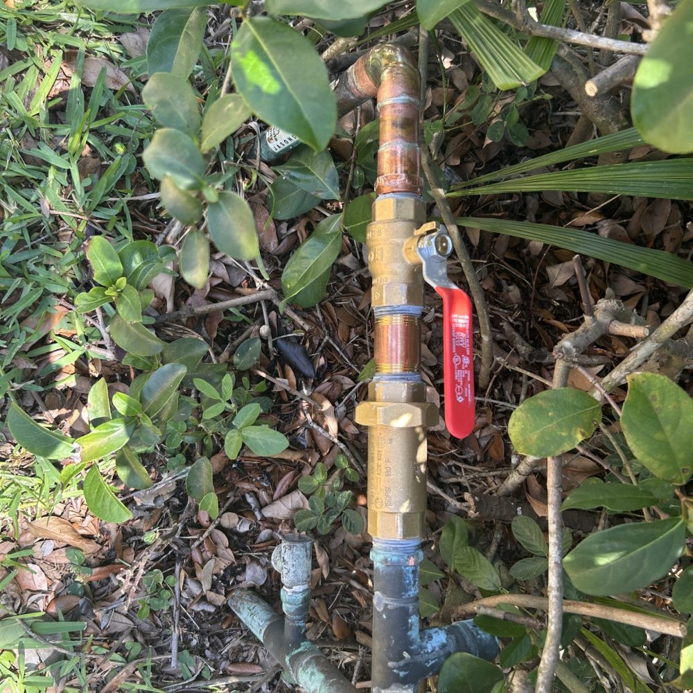 Residential outdoor water shutoff valve with copper plumbing pipes and brass fittings.